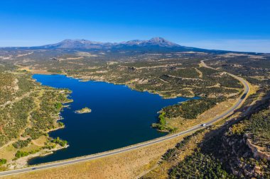 Amerikan tabiatının havadan görünüşü. Mavi gökyüzü ve göl, otoyol ve arabalar. ABD 'nin Utah eyaletindeki rezervuarı ele geçirin.
