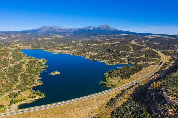 Amerikan tabiatının havadan görünüşü. Mavi gökyüzü ve göl, otoyol ve arabalar. ABD 'nin Utah eyaletindeki rezervuarı ele geçirin.