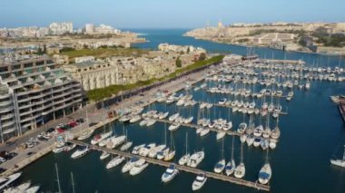 Msida marinasının, yatların, teknelerin havadan görüntüsü. Güneşli bir gün, Valletta City arka planda. Kamera ileri gidiyor. Malta ülkesi