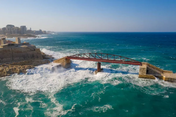 Aerial top view of the waves on the red Breakwater Bridge during stormy weather. Valletta city, Malta island