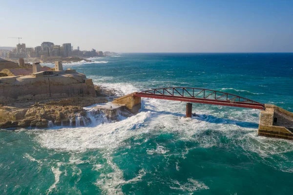 Aerial top view of the waves on the red Breakwater Bridge during stormy weather. Valletta city, Malta
