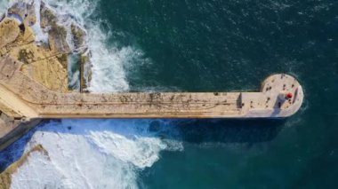 Kızıl deniz fenerinin havadan görünüşü, büyük fırtınalı dalgalar, Akdeniz. Fort Ricasoli, Grand Harbor. Kamera yukarı çıkıyor. Malta adası