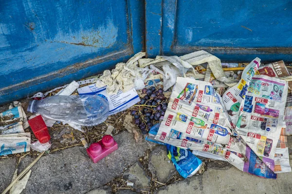 Nápoles, Italia - 11 de agosto de 2015: Mucha basura y uvas están en la carretera frente a una puerta de metal . — Foto de Stock