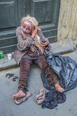 Roma - 18 Haziran 2014: Evsiz bir kadın bira içiyor ve makyaj yapıyor.