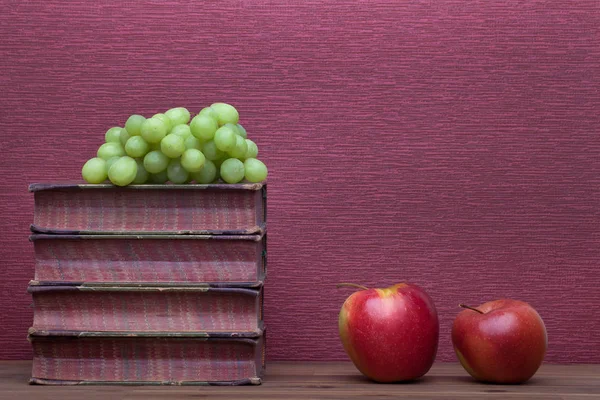 Old books, apple and grapes