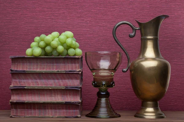 Renaissance, verre à vin rummer, carafe en laiton, vieux livres et raisins — Photo
