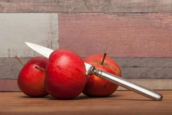 Red apple on the wooden table, cut with the knife — Stock Photo, Image