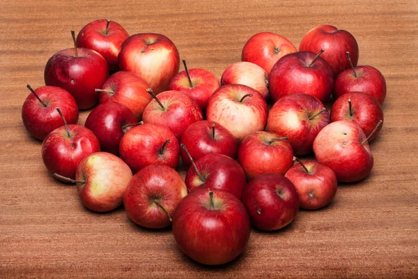 Organic apples, apple in a heart shape on wooden table — Stock Photo, Image