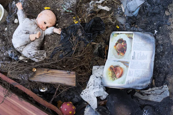Vieja muñeca sucia y libro en un suelo quemado — Foto de Stock