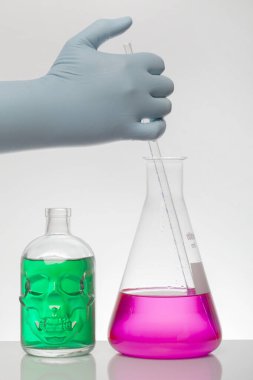 Laboratuvar eldivenlerindeki bir el kimyayı karıştırır. Laboratuvar şişelerinde sıvı. Bilimsel biyokimya laboratuvarı. Renkli sıvı.