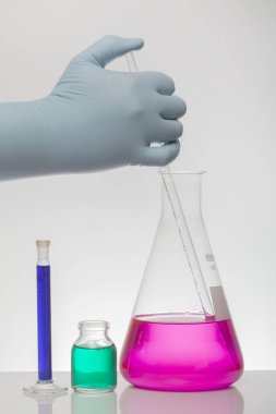 Laboratuvar eldivenlerindeki bir el kimyayı karıştırır. Laboratuvar şişelerinde sıvı. Bilimsel biyokimya laboratuvarı. Renkli sıvı.
