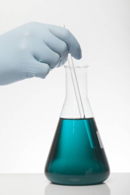 Laboratuvar eldivenlerindeki bir el kimyayı karıştırır. Laboratuvar şişelerinde sıvı. Bilimsel biyokimya laboratuvarı. Renkli sıvı.