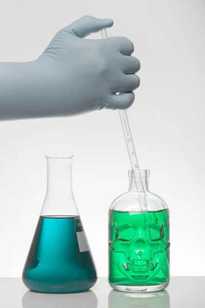Ένα χέρι στα εργαστηριακά γάντια αναμιγνύει τη χημεία. Υγρό σε εργαστηριακές φιάλες. Επιστημονική βιοχημικό εργαστήριο. Πολύχρωμο υγρό. — Φωτογραφία Αρχείου