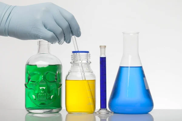 Una mano en guantes de laboratorio mezcla química. Líquido en botellas de laboratorio. Laboratorio científico bioquímico. Colorido líquido . —  Fotos de Stock