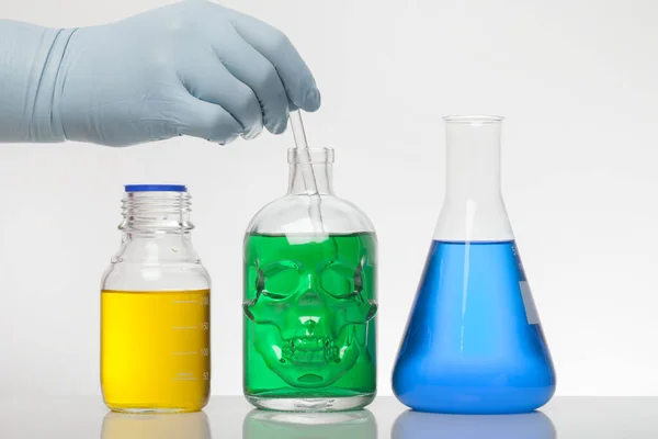 Ręka w rękawiczkach laboratoryjnych miesza chemię. Płyn w butelkach laboratoryjnych. Laboratorium biochemiczne. Kolorowy płyn. — Zdjęcie stockowe