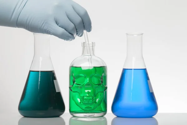 Una mano in guanti da laboratorio mescola chimica. Liquido in bottiglie da laboratorio. Laboratorio biochimico scientifico. Liquido colorato . — Foto Stock