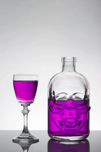 Una botella de cráneo y vasos de cristal con un líquido, bebida alcohólica . — Foto de Stock