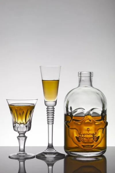 A skull bottle and crystal glasses with a liquid, alcohol drink. — Stock Photo, Image