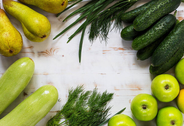 Fresh green vegetables and fruits - pears, zucchini, cucumbers, green onions, dill, parsley, apples on the wooden white background. Concept healthy food photo