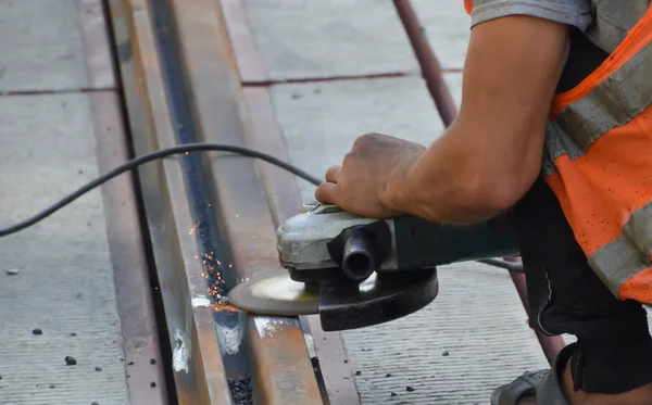 worker grinds welded rails joint