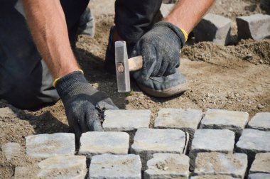 Çekiçli bir işçi taş kaldırım döşedi.