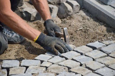 Çekiçli bir işçi taş kaldırım döşedi.