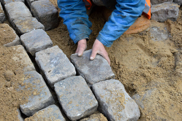 A worker lays paving stones