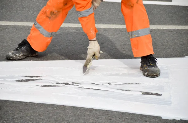 Road worker marking up with white paint