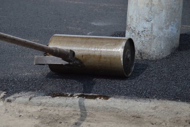 Yol yapımı. Asfalt yerleştirmek için elle silindir.