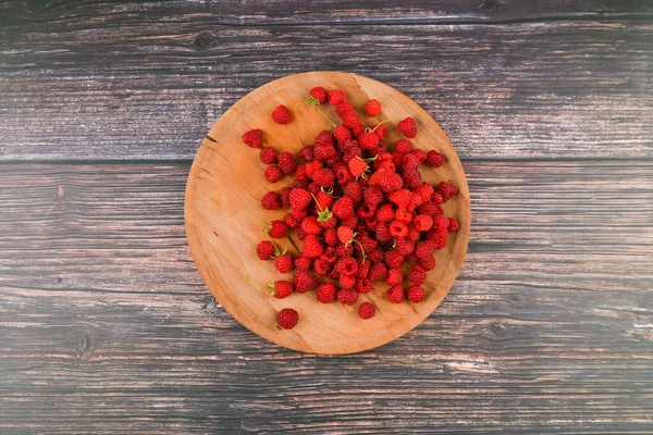 Maliny na dřevěném talíři. Dřevěný kulatý, plochý talíř. na dřevěném pozadí. Dřevěné bloky se slovy Vitamin C, čerstvé ovoce v pozadí, zdravé jídlo nebo dietní koncept. Pohled shora. — Stock fotografie