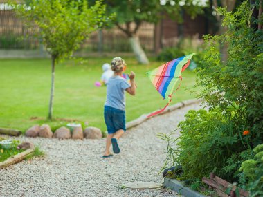 Yaz filmi. Güneş gözlüklü mutlu bir çocuk deniz kıyısında koşar ve gün batımında çok renkli bir uçurtma fırlatır.