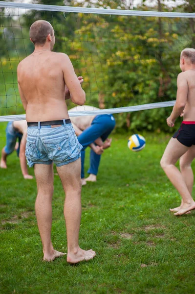 Les jeunes garçons jouent au volley-ball dans la nature, les sports actifs sur la pelouse, jouer sur le net — Photo