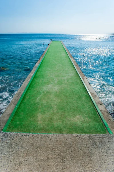 Green Pier Concrete pier over blue waters, pier with green carpet