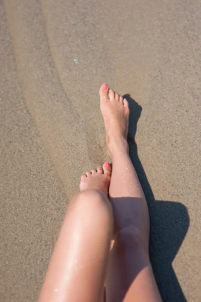 Jovem mulher pernas banhos de sol na praia — Fotografia de Stock