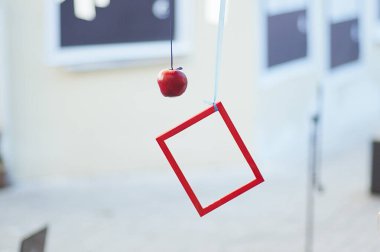 Kırmızı çerçeve ağırlığında, asılı kırmızı elma. Sokak sanatı.