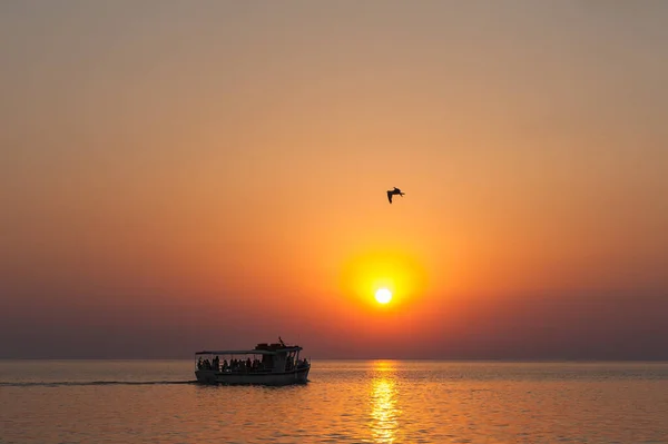 La barca al tramonto, con i turisti al tramonto, nuotare sotto il sole cocente, un favoloso tramonto sul mare . — Foto Stock