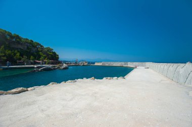 Boş iskele, beton iskele, su bina ve açık havuz ile çevrili.