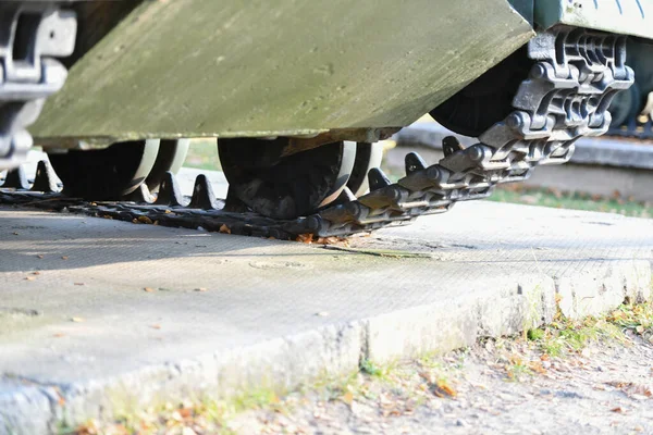 Ruedas cisterna en primer plano. Huellas de hierro de un tanque militar pesado. Orugas de hierro y ruedas de un tanque pesado militar. Vista de la parte frontal de la oruga verde del tanque de pie en el suelo wi —  Fotos de Stock