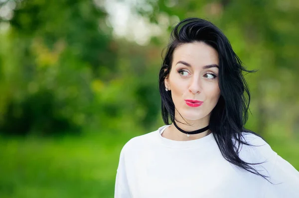 Retrato de uma menina alegre na natureza. com cabelo preto e capuzes pintados em uma camiseta branca. emoções naturais. Menina sorridente bonita com olhos abertos . — Fotografia de Stock