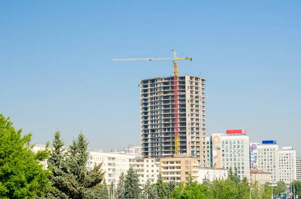 Construction of tall buildings, yellow-red crane towering