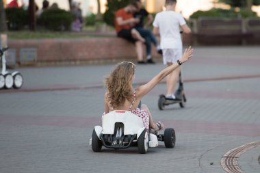 Elektrikli arabadaki kız. Parkta eğlenmek. Elektrikli araçlarda eğlence. küçük elektro formülü