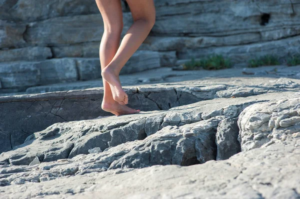 La ragazza va a piedi nudi sulle rocce, arrampicandosi — Foto Stock