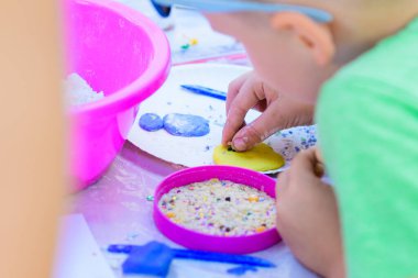 Çocuk, plastikten figürler yapıyor. Gelişim merkezi. Engelli çocuklara yardım et. Üç yaşında güzel bir kız masada oturuyor ve renkli kilden figürler yapıyor. Heykel ve çil