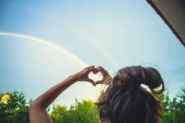 heart made of hands on a rainbow background. LGBT flag painted in the shape of a heart. symbolism of the world.