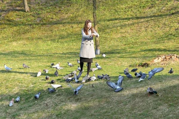 Meisje voedt vogels bij zonnig weer. Mooie jonge vrouw voeden vogels in het park op zonnige herfstdag — Stockfoto