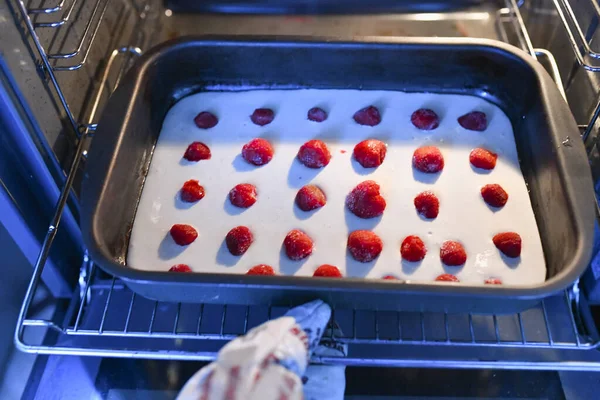 Положи ягодный пирог в духовку. Женщина-пекарь кладет в духовку печенье с клубникой. Рецепт пирога. Домашняя выпечка . — стоковое фото