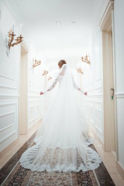 Beyaz elbiseli bir kız beyaz bir koridorda yürüyor. Koridorda elbisesiyle yürüyen güzel bir moda kızı. Antik çağlardan kalma kıyafetler. Tarihi çağ. Yukarıdan görünüm.