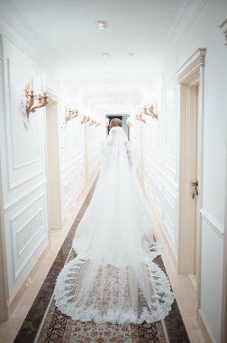 Beyaz elbiseli bir kız beyaz bir koridorda yürüyor. Koridorda elbisesiyle yürüyen güzel bir moda kızı. Antik çağlardan kalma kıyafetler. Tarihi çağ. Yukarıdan görünüm.