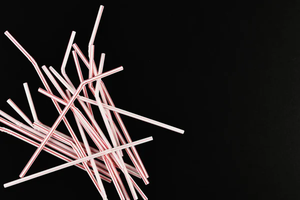 Plastic tubules on a black background. randomly scattered. place for an inscription. view from above — Stock Photo, Image