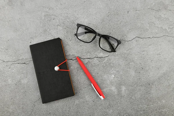 Gafas con cuaderno sobre fondo gris. Escritorio de oficina con accesorios de negocios. Vista superior —  Fotos de Stock